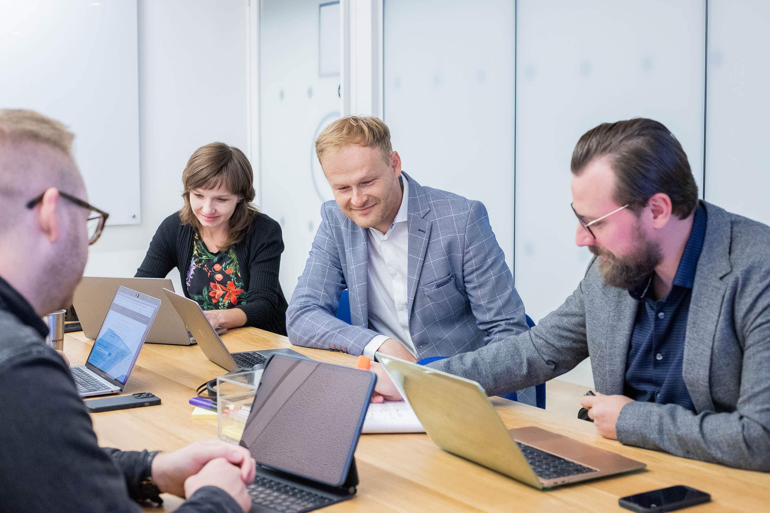 four people with laptops talking on table